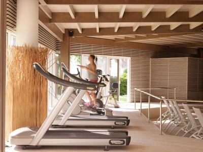 Persona si allena su un tapis roulant in una palestra luminosa con accenti in legno e sedie a sdraio.