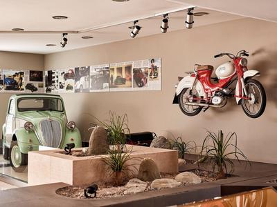 Retro-Auto und Motorrad als Dekoration in einer hellen Hotel-Lobby mit Pflanzen.