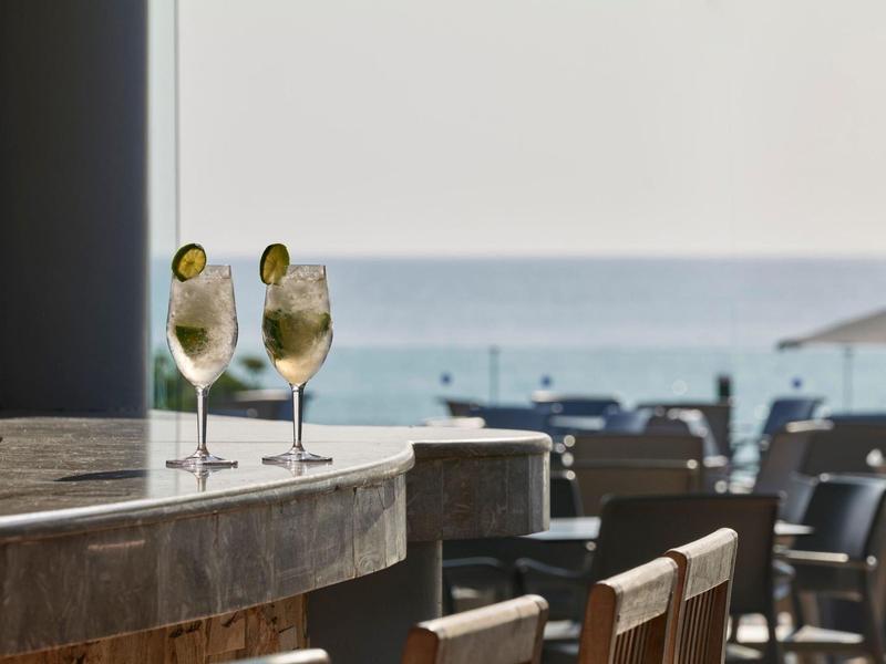 Due cocktail con fette di lime su un bar con posti a sedere e vista sul mare.