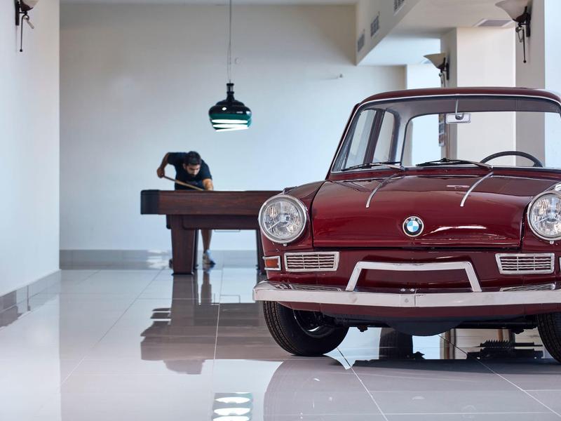 Auto d'epoca rossa in una stanza luminosa con un tavolo da biliardo sullo sfondo.