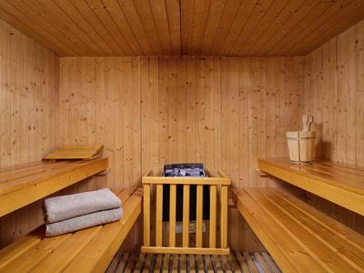 Cozy wooden sauna room with benches, towels, and sauna stove with bucket and ladle.