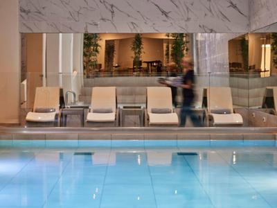 Indoor pool with loungers and a person in a stylish hotel interior