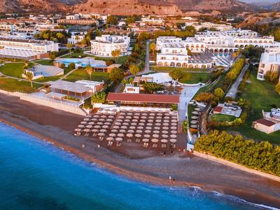 Strandhotel mit vielen Sonnenschirmen am klaren blauen Meer und umliegender Vegetation.