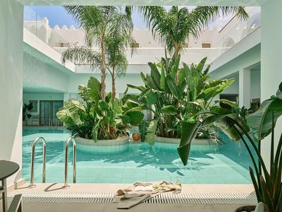 Innenhof mit kleinem Pool, tropischen Pflanzen und modernen Sitzgelegenheiten in einem Hotel.