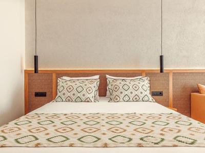 Modern hotel room with a double bed, geometric patterned bedding, and pendant lights.