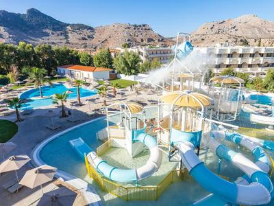 Parco acquatico con scivoli e piscina davanti a edifici dell'hotel in area montuosa soleggiata.