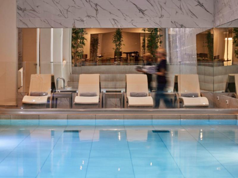 Indoor pool with loungers and a person in a stylish hotel interior