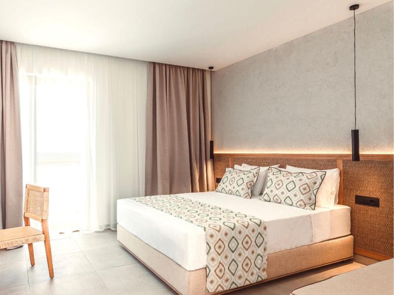 Modern bedroom with a large bed, wooden headboard, pendant lights, and floor-to-ceiling window.