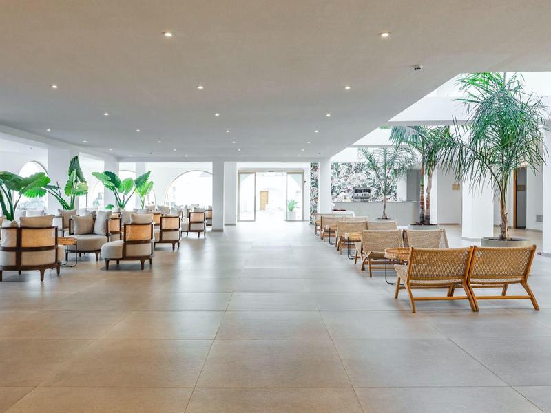 Spacious hotel lobby with modern seating, large plants, and bright natural light.
