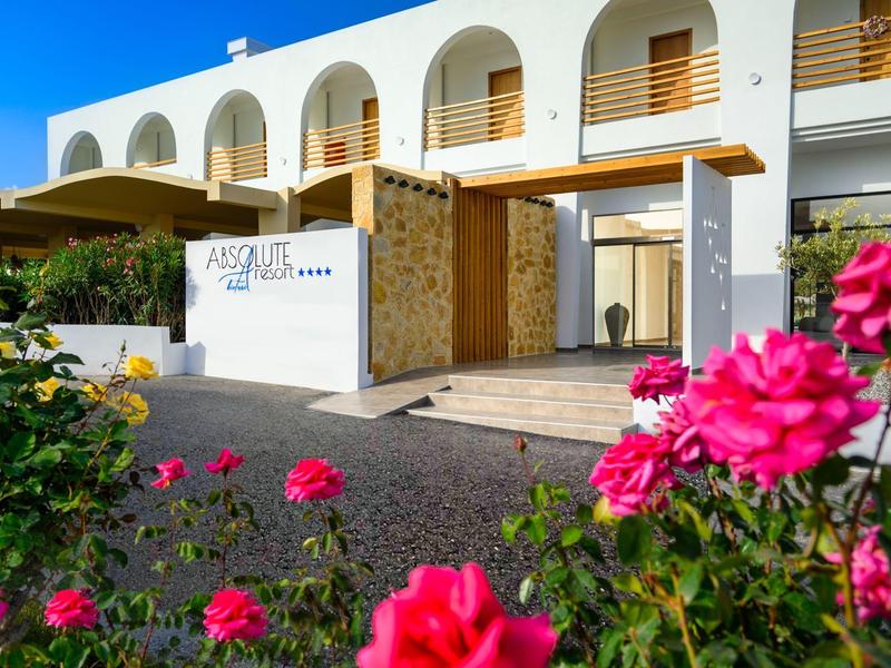 Modern hotel building with white walls, wooden accents, and pink flowers in the foreground.