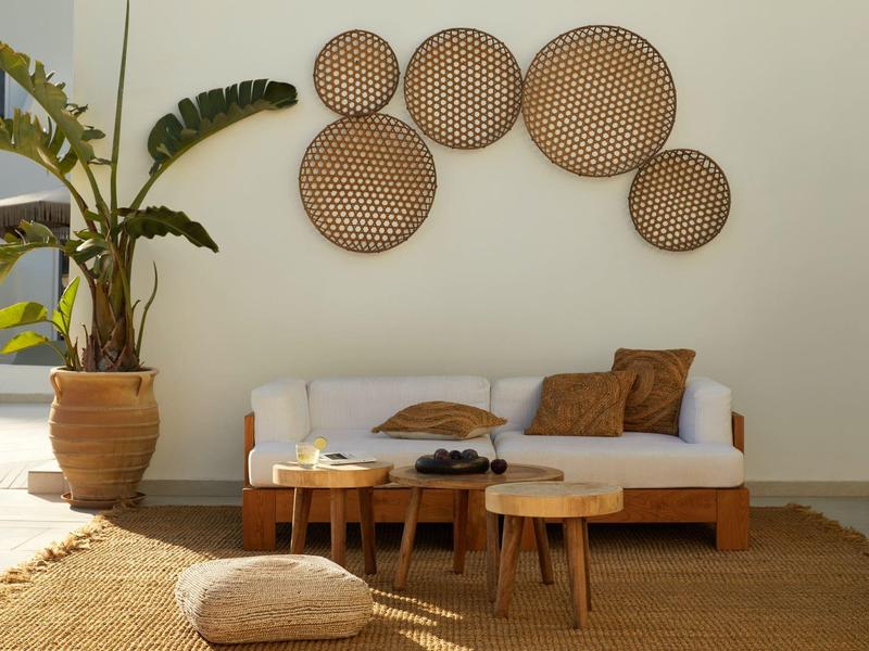 Cozy seating area with wooden furniture, potted plant, and round woven wall decorations.