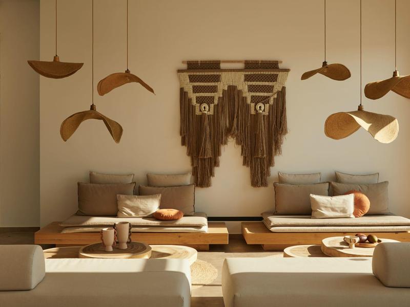 Modern living room with beige sofa, wooden bench, and wall art in warm earth tones