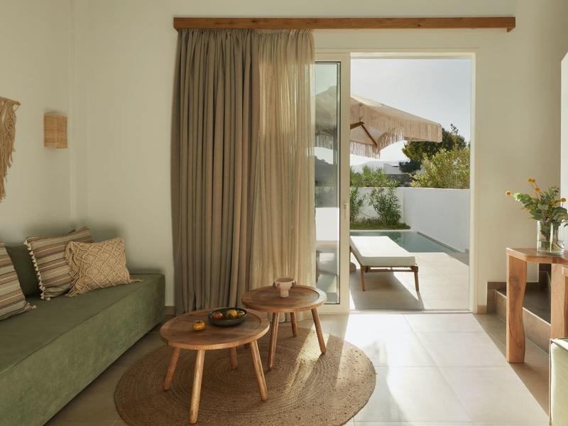 Cozy living room with green sofa, wooden tables, and terrace access with lounge chair.