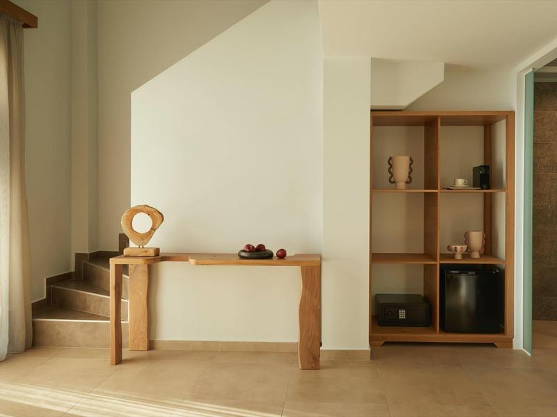 Bright entrance area with wooden stairs, console table, and shelving in muted tones.