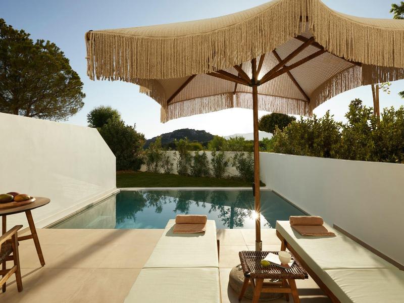 Quiet pool area with lounge chairs and sun umbrella on a sunny day.
