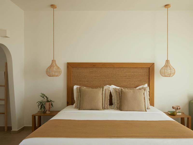 Bedroom with a double bed, wooden headboard, and two hanging lights on the wall.