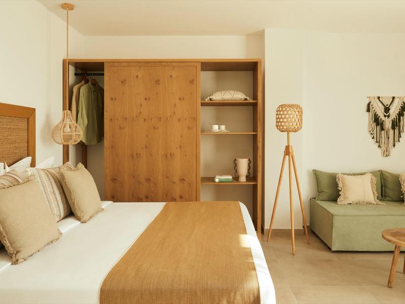 Modern bedroom with double bed, wooden wardrobe, and cozy seating area.
