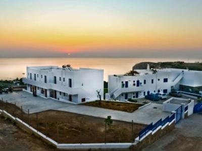 Moderno complejo hotelero blanco junto a la costa al atardecer.