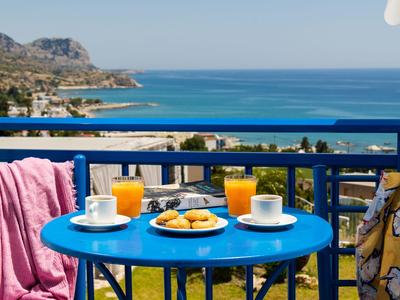 Mesa azul con desayuno en balcón con vistas al mar y montañas