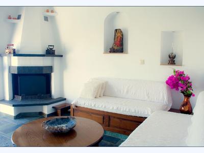 Pohodlný obývací pokoj s krbem, bílými pohovkami a barevnou květinovou kyticí na dřevěném stole