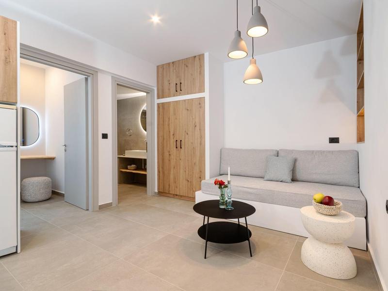 Moderně zařízený obývací pokoj s pohovkou, konferenčními stolky a přístupem do koupelny a ložnice