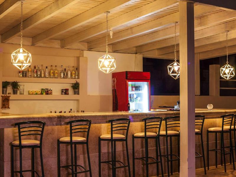 Accogliente bar dell'hotel con soffitto in legno, sgabelli alti e lampade sospese moderne.