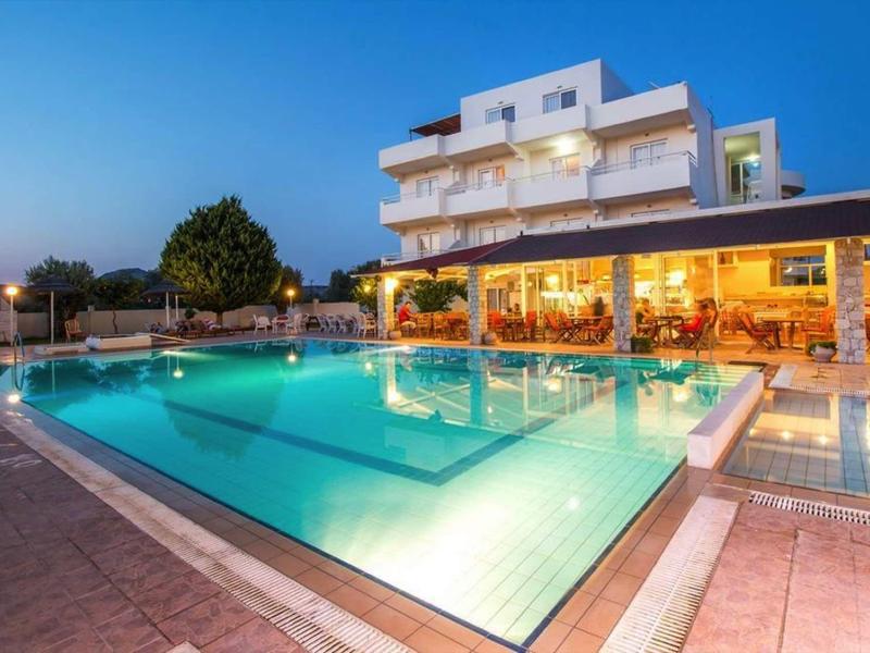 Complesso alberghiero moderno con piscina esterna illuminata al tramonto e area ristorante accogliente.