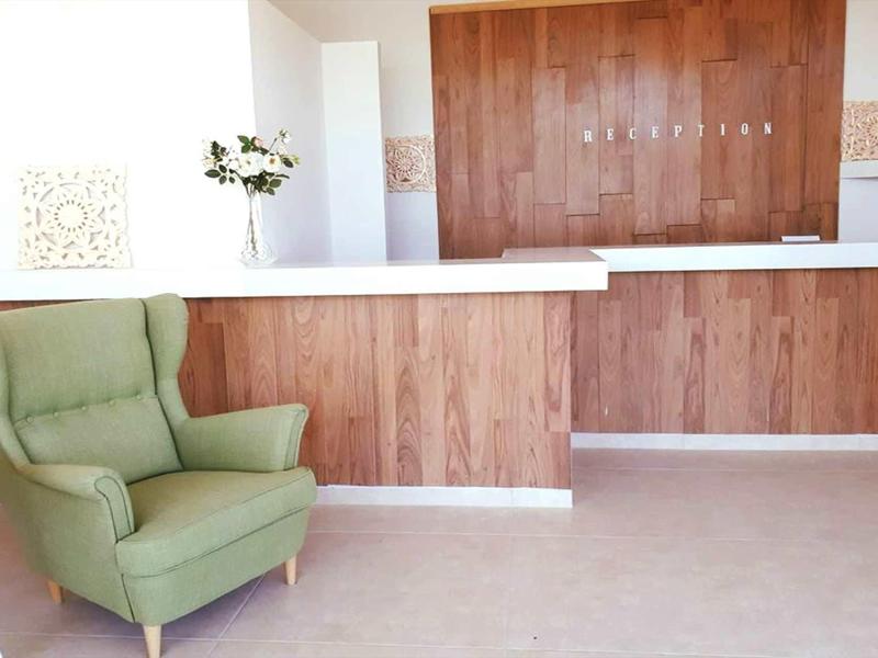 Area d'attesa luminosa con poltrona verde e parete in legno sullo sfondo