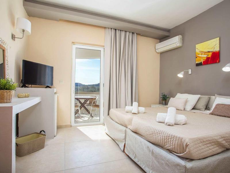 Camera d'hotel luminosa con letto matrimoniale, balcone e arredi moderni.