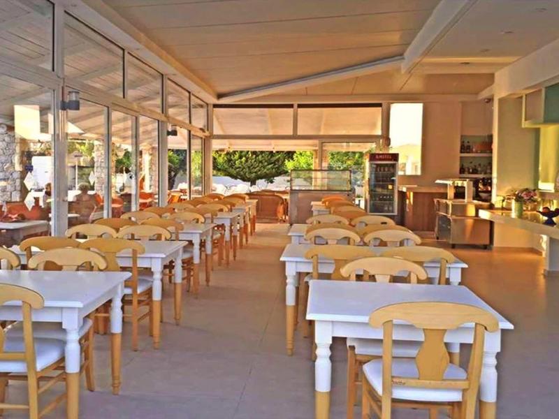 Ristorante luminoso e aperto con sedie e tavoli in legno disposti in file, invitante per gli ospiti.
