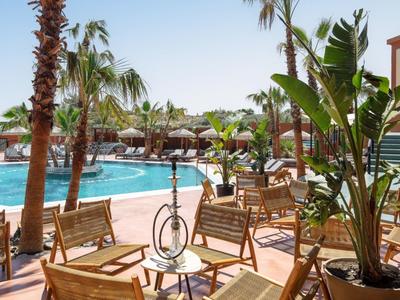 Area piscina con lettini e narghilé in un contesto alberghiero tropicale