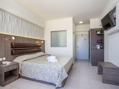 Camera d'hotel moderna con letto matrimoniale, comodini, TV a parete e piccolo tavolo.