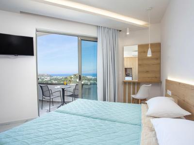 Camera d'hotel moderna con letto matrimoniale, balcone e vista mare alla luce del giorno.