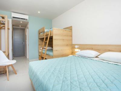 Camera luminosa arredata con letto matrimoniale, letto a castello e decorazioni minime.