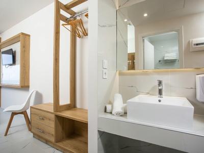 Bagno moderno e ingresso con dettagli in legno e lavabo bianco.