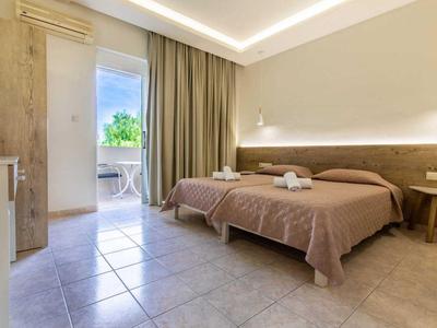 Una camera d'hotel luminosa con due letti singoli e accesso a un balcone con vista.