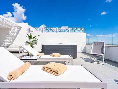 Terrazza panoramica moderna con mobili bianchi, asciugamani e ombrellone sotto un cielo sereno