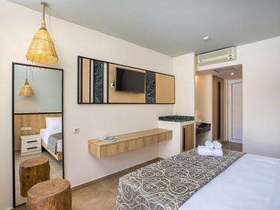 Camera d'hotel moderna con TV a muro, grande specchio, comò e letto confortevole.