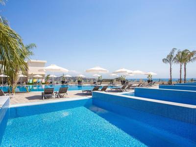 Piscina esterna moderna con lettini e palme in una giornata soleggiata