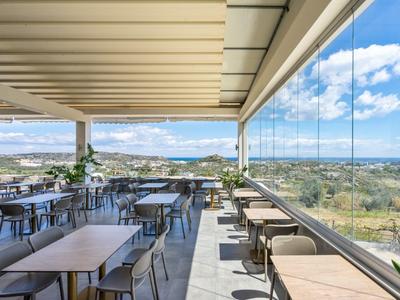 Terrazza esterna coperta con tavoli e sedie con vista panoramica sul paesaggio.