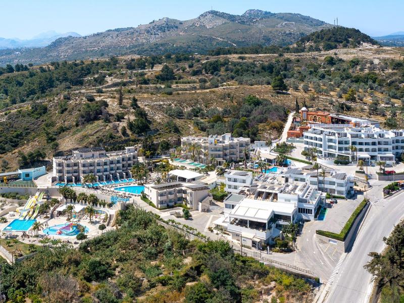 Vista aerea di un hotel con diverse piscine in un paesaggio collinare.
