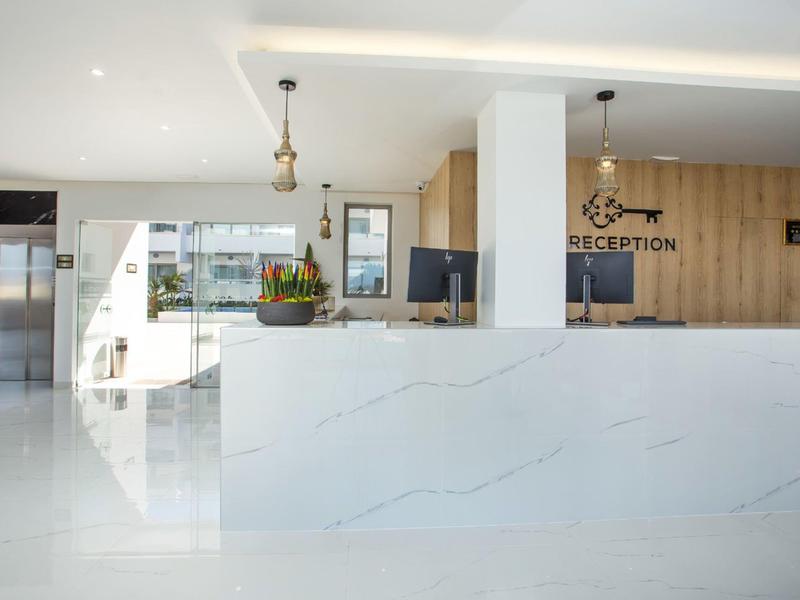 Reception d'hotel moderna con bancone in marmo bianco e accenti in legno.