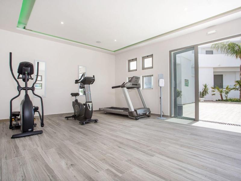 Palestra luminosa con tapis roulant, cyclette e ellittica accanto a grandi finestre con vista sul cortile.