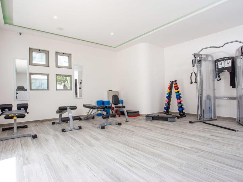 Sala fitness luminosa con attrezzature per allenamento e pesi in un hotel moderno