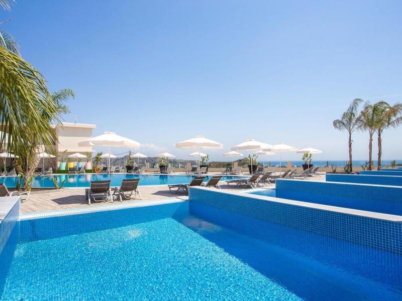 Piscina esterna moderna con lettini e palme in una giornata soleggiata