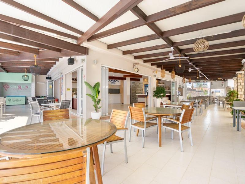 Ristorante luminoso e spazioso con tavoli in legno, sedie e decorazioni moderne in un hotel.