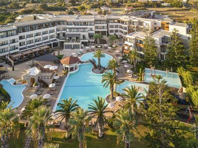 Grand hôtel avec plusieurs piscines et palmiers dans une zone de vacances ensoleillée.