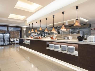 Nowoczesna strefa bufetu hotelowego z licznymi lampami i podświetlanymi półkami.