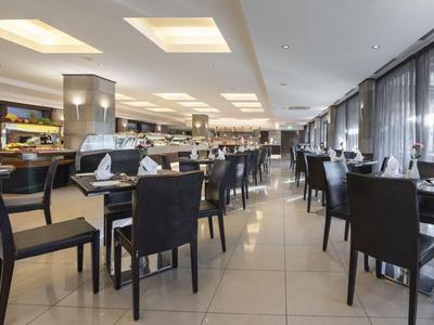 Restaurant d'hôtel moderne avec des chaises noires et de grandes fenêtres avec rideaux