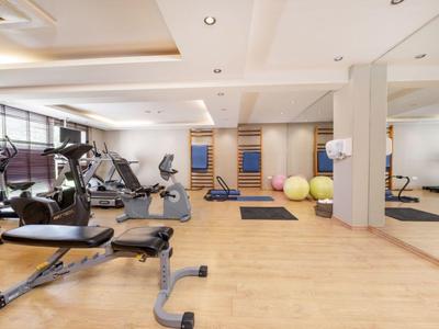 Salle de sport moderne avec différents équipements d'entraînement et tapis de yoga dans un hôtel.